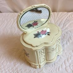 an old fashioned vanity with a mirror on it's lid and flowers painted on the side