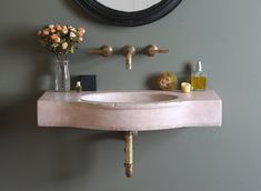 a bathroom sink sitting under a mirror next to a vase with flowers