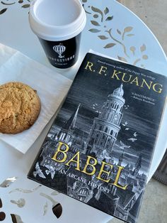 a cup of coffee, cookie and book on a table