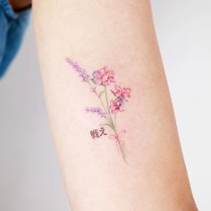 a small flower tattoo on the right arm and leg, with chinese characters written below it