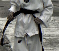 a man in white and black outfit holding a black belt