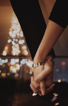 two people holding hands in front of the eiffel tower at night, paris