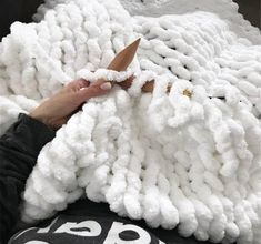 someone is cutting through the yarn on top of a large white blanket that has been made into a sheep