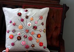 a decorative pillow with buttons on it sitting on a chair next to a wooden headboard