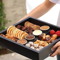 a person holding a tray filled with different types of food