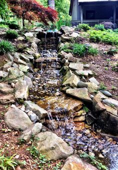 there is a small waterfall in the middle of some rocks and water flowing down it