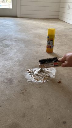 a person using a brush to clean an area in the floor that has spilled paint on it