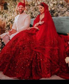 a man and woman dressed in red sitting on a couch with christmas decorations behind them