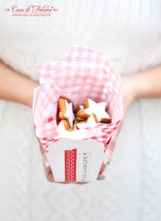 a person holding a paper box filled with cookies and marshmallows in it