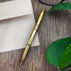 a pen sitting on top of an envelope next to a plant