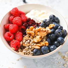 a bowl filled with berries, yogurt and granola on top of a table