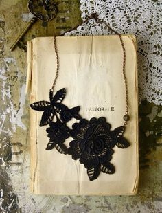 an old book with some black lace on it and a necklace hanging from the front