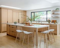 a large kitchen with wooden cabinets and white counter tops, along with two bar stools