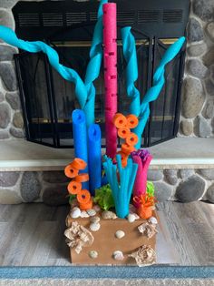 an arrangement of fake corals and seaweed in front of a fire place with a fireplace