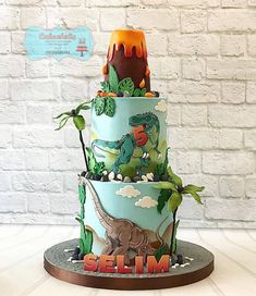 a three tiered cake decorated with dinosaurs and plants