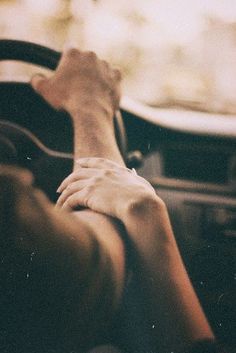 a black and white photo of someones hand on the steering wheel