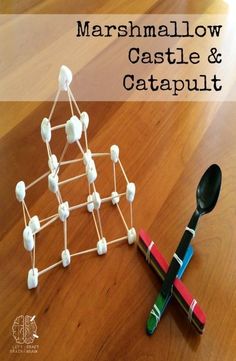 marshmallow castle and catapult made out of pops sticks on a wooden table