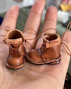 a hand holding two small brown baby boots