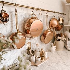 pots and pans are hanging on the wall in this kitchen with marble countertops