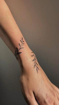 a person's hand with a small tattoo on the wrist and an olive branch