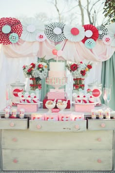 a table topped with lots of cakes and cupcakes next to dessert boxes filled with candies