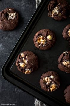 chocolate cookies are on a baking sheet with white crumbs