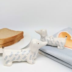 a white plate topped with bread next to two dachshund figurines