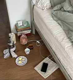 an unmade bed sitting on top of a wooden floor next to a pile of books