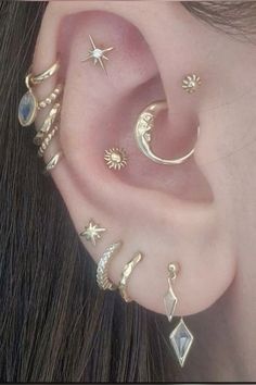 a woman wearing ear piercings with stars and moon designs on her ears, all in gold