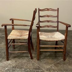 two wooden chairs sitting next to each other on top of a tile floor in front of a wall