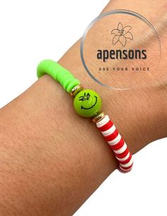 a person wearing a green bracelet with a smiley face bead on it's wrist