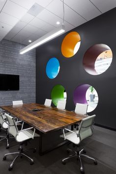 an empty conference room with colorful circles on the wall and white chairs around a wooden table