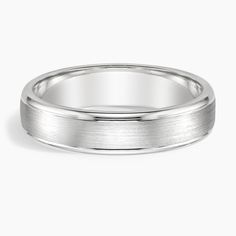 a white gold wedding ring on a plain surface