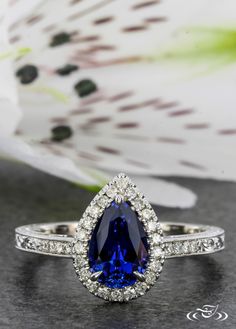 a blue and white ring sitting on top of a black surface with flowers in the background