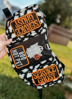 someone holding up a black and white hat with orange writing on it that says service ghost