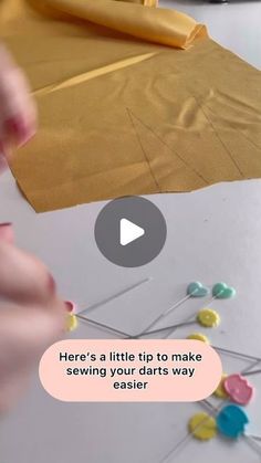 someone is making something out of paper and some pins on the table with a yellow bag