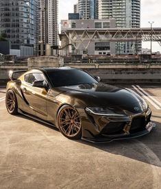 a black and gold sports car parked in front of some tall buildings on a city street