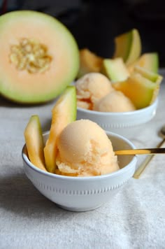 two white bowls filled with ice cream next to an avocado cut in half