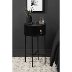 a black side table with two glasses on it and a plant in the corner next to it