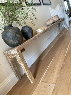 a wooden bench with two vases on top of it next to a wood floor