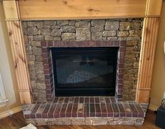 a stone fireplace with wooden mantle and wood flooring