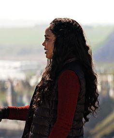 a woman standing on top of a hill with a cell phone in her hand,