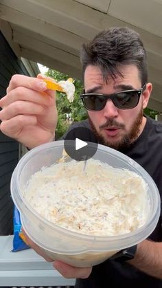 a man in sunglasses is holding a bowl of food