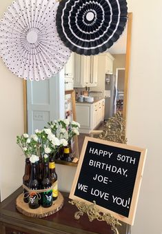 a birthday party with beer bottles, flowers and paper fan decorations on a table in front of a mirror