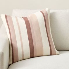 a white couch with a pink and brown striped pillow on it's backrest