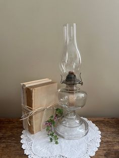 a glass lamp sitting on top of a wooden table next to a box and book