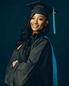 a woman wearing a graduation cap and gown with her arms crossed, smiling at the camera