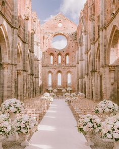 the aisle is lined with white flowers and vases on either side of the aisle