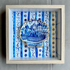 a blue and white plate with a train on it in a wooden frame hanging on the wall