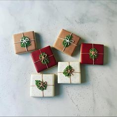 four presents wrapped in brown and white paper with green bows are sitting on a marble surface